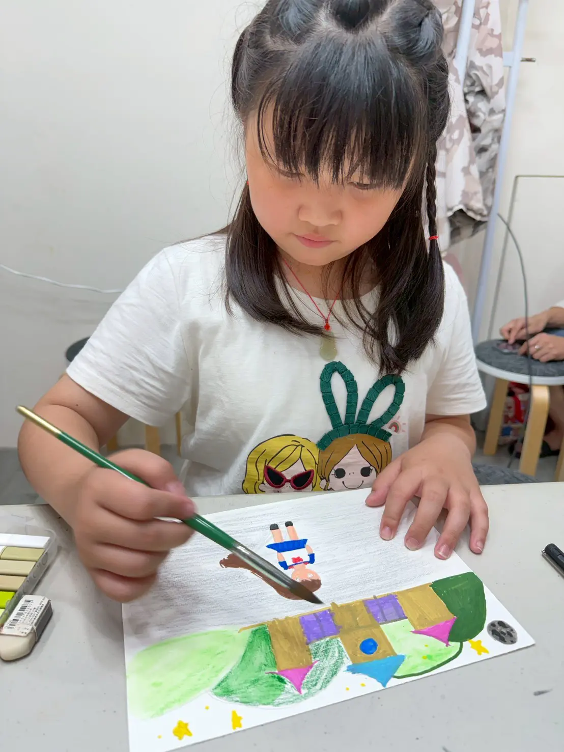 孩子拿著水彩筆，專心在自己的手繪草圖上上色