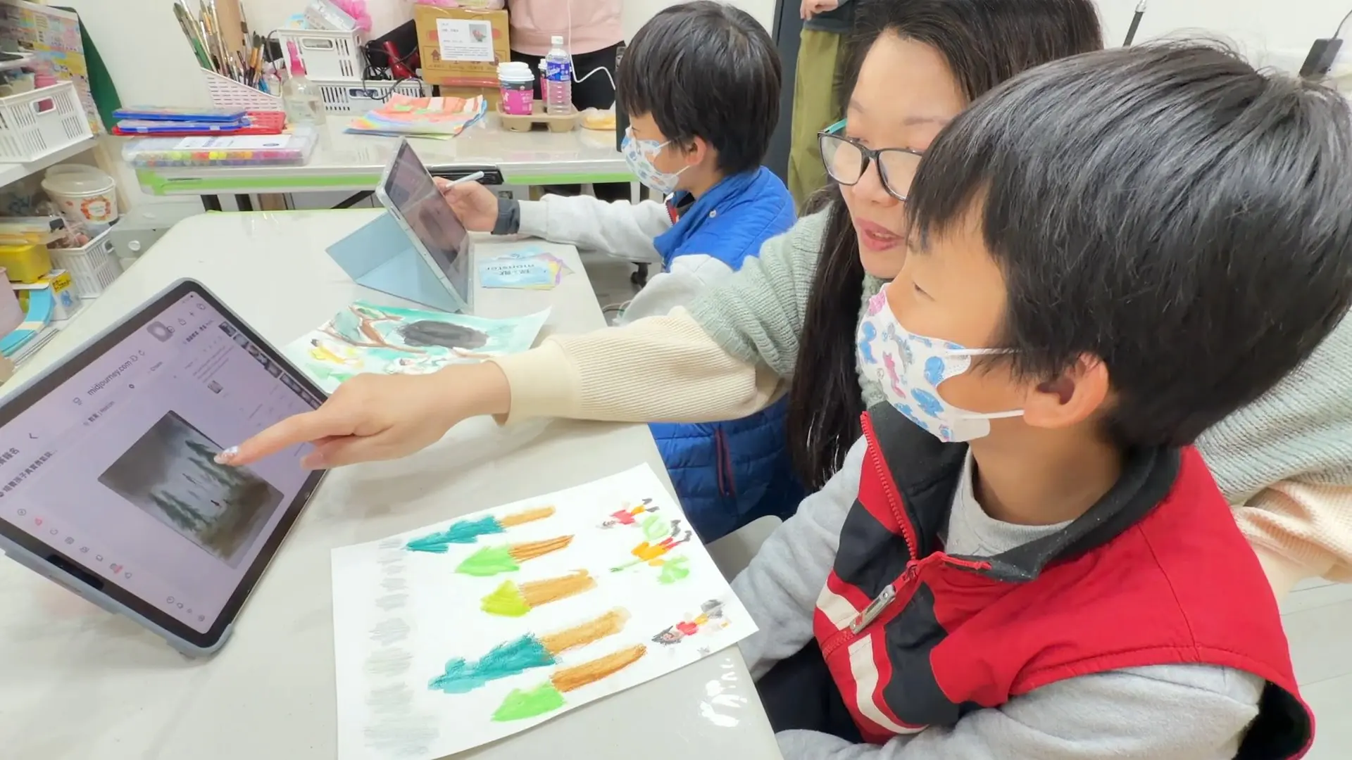 老師陪孩子看平板上的 AI 生成結果，桌上放著孩子的手繪草圖